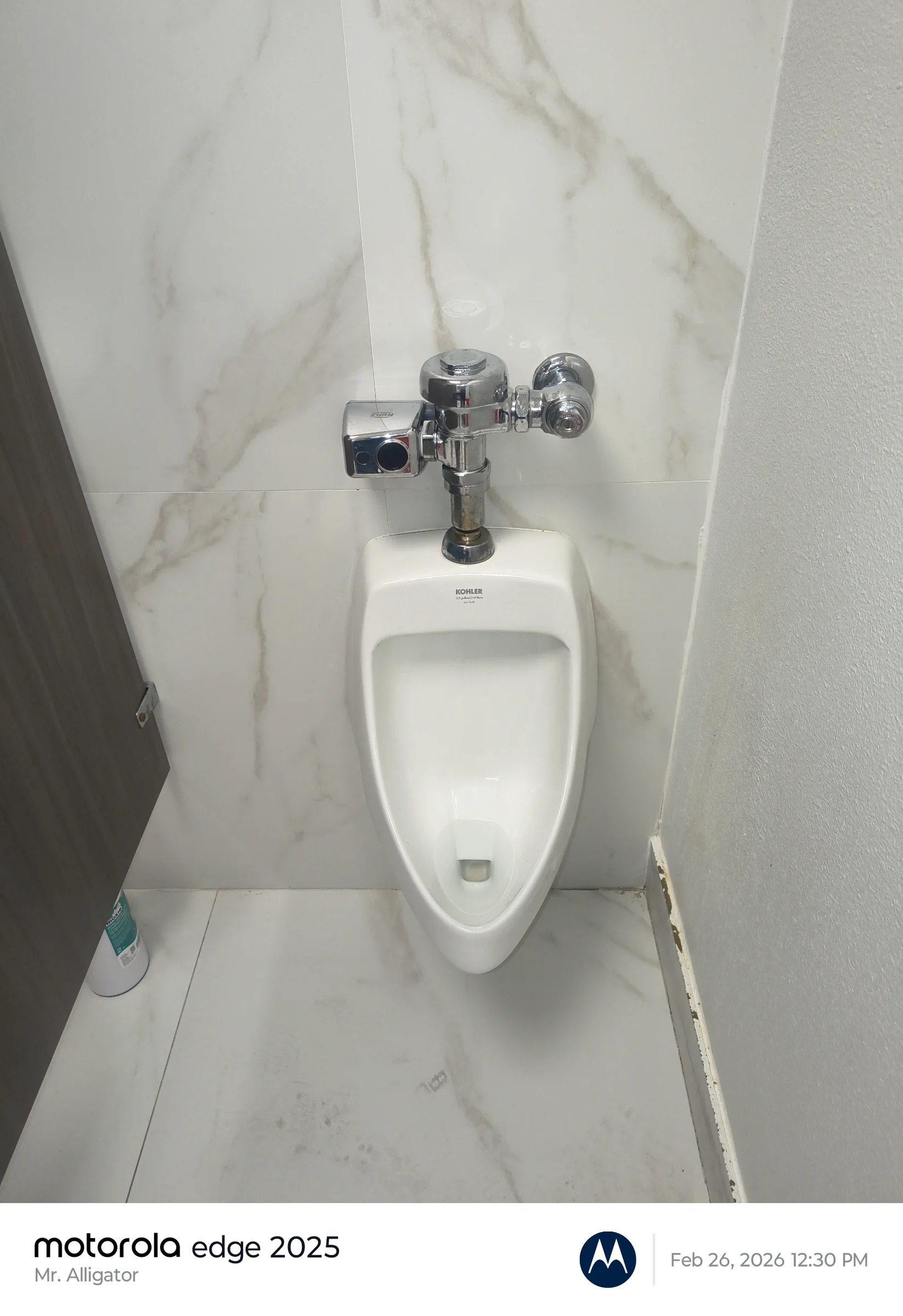 Wall-mounted commercial urinal against porcelain tile